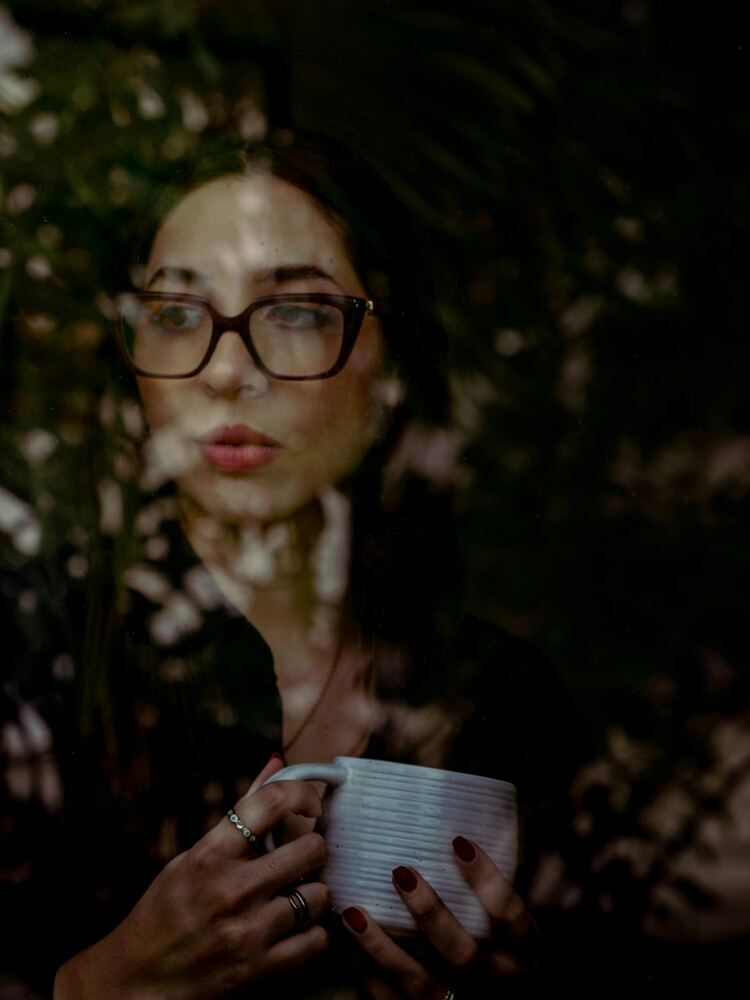 Mujer en un momento de reflexión junto a la ventana, reconociéndose